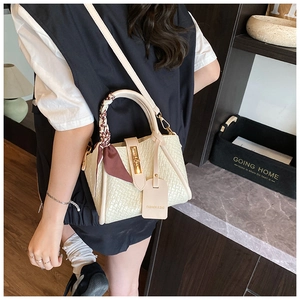 Detail of beige woven leather bucket bag featuring a silk scarf and gold metal lock