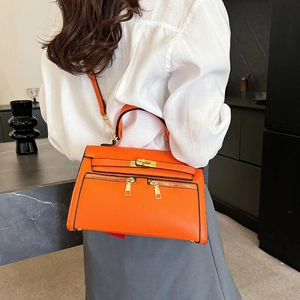 Modieuze oranje trapezium handtas met goudkleurige details in een lifestyle setting