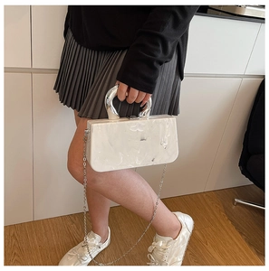 Details der weißen Acryl-Clutch mit Marmormuster, hufeisenförmigem Griff und Metallkette