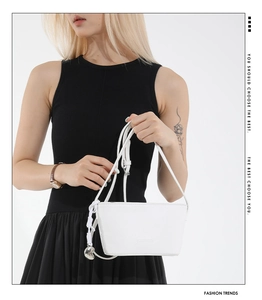 Detail of white litchi pattern bag featuring a rope knot and silver heart charm decoration