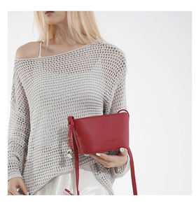 Detail of red textured leather bucket bag featuring embossed text and metal ball charm