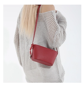Detail of red pebbled leather bucket bag with knotted strap and minimal fashion engraving