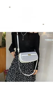 Detail of white leather crossbody bag with blue and black woven flap and gold buckle