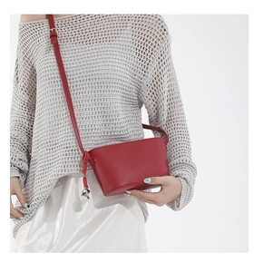 Detail of red lychee pattern leather crossbody bag with metal ball charm and fashion logo