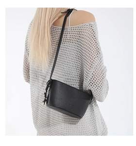 Close-up of black litchi grain leather crossbody bag with knot detail on the side