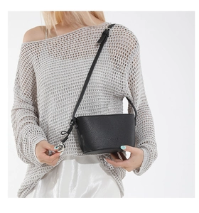 Detail of black lychee grain leather crossbody bag with silver sphere charm and strap