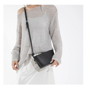 Detail of black lychee grain leather bucket bag with silver charm on adjustable strap