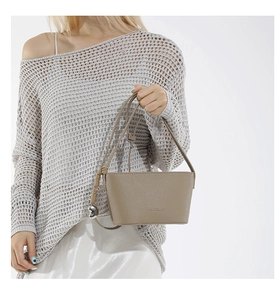 Detail of taupe pebble leather bucket bag featuring a knot tassel and silver charm
