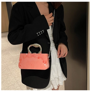 Rosa Acryl-Clutch mit Marmormuster, silbernem Metallgriff und Kette am Model