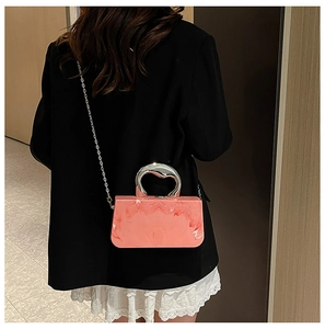 Nahaufnahme der rosa marmorierten Acryl-Clutch mit Silbergriff am Modell getragen