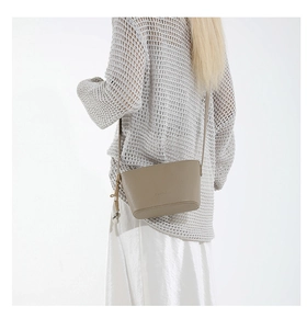 Detail of taupe pebbled leather crossbody bag with knot decor and fashion lettering