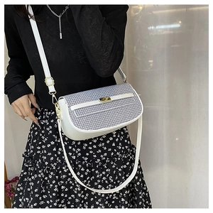 Detail of white leather crossbody bag featuring geometric pattern flap and gold hardware