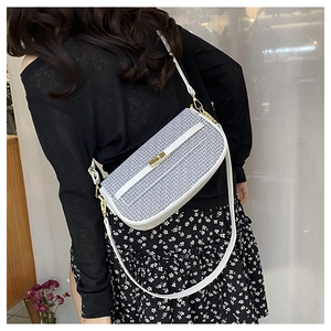 Detail of white leather and blue woven fabric crossbody bag with golden twist lock