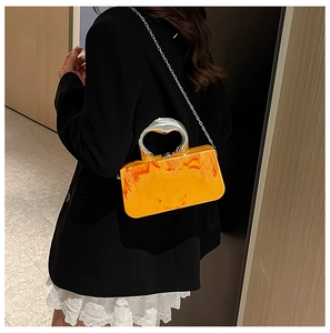 Detail der orangefarbenen Acryl-Boxtasche mit Marmormuster und Metallgriff