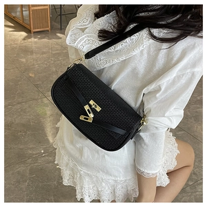 Detail of black woven shoulder bag featuring a modern gold-tone twist lock closure