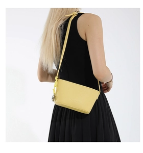 Detail view of lemon yellow bucket bag with lychee texture and round metal pendant charm