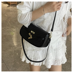 Detail view of black woven texture crossbody bag with iconic gold clasp and leather strap