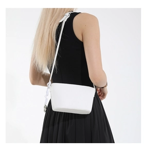 White pebbled leather bucket bag with knot detail and metal charm on a fashion model