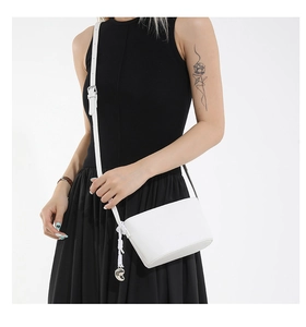 Detailed shot of white lychee leather texture and silver heart charm on crossbody bag