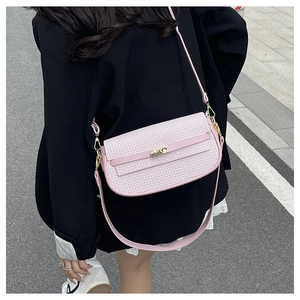 Close-up of pink textured crossbody bag with gold buckle on a black blazer outfit
