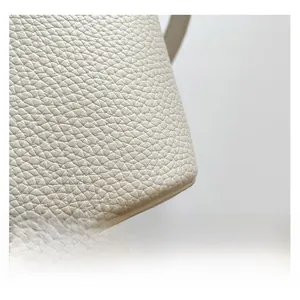 Close-up of premium lychee texture leather and precise stitching on the white bucket bag