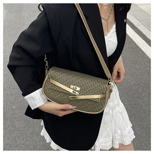 Close-up of golden textured handbag with metal buckle and strap on a street model