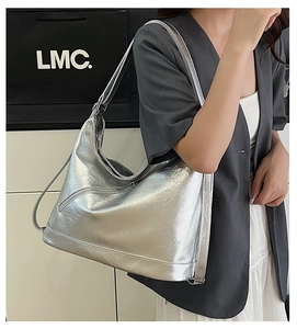 Model wearing silver metallic tote bag with wrinkled texture and adjustable strap