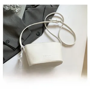 Detail of white lychee leather bucket bag with silver heart charm and braided knot detail