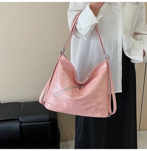 Detail of light pink high-capacity leather tote showing cracked oil-wax texture and zippers