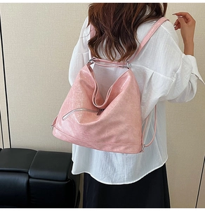 Detail of light pink crinkled leather backpack with silver zippers on a model