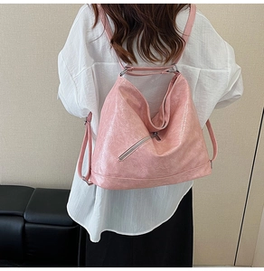 Detail of pink pleated PU leather tote bag showing crossbody strap and diagonal zipper
