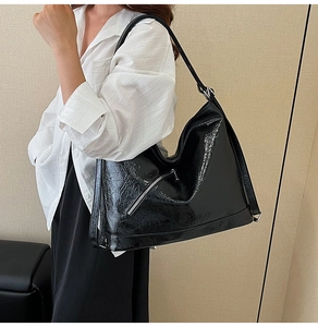 Black glossy tote bag with oil wax texture and silver zipper shown on female model