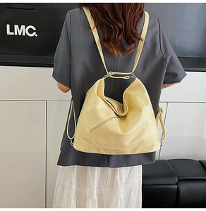 Rear view of a model wearing a large cream yellow glossy PU leather backpack with zippers