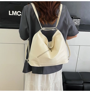 Detail view of cream-white leather backpack with metallic zipper and adjustable straps
