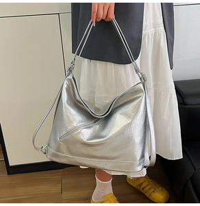 Silver PU tote bag with metallic crinkle texture and diagonal zippers on model