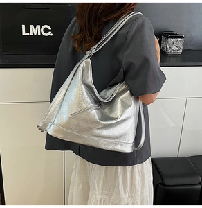 Detail of silver metallic hobo bag featuring premium pleated texture and wide shoulder strap