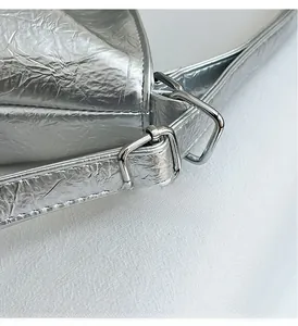 Macro view of adjustable silver metal buckle and pleated leather texture on a tote bag