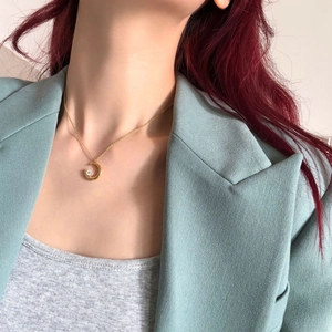 Close-up of elegant gold crescent moon pendant necklace with inset zircon on a model