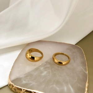 Close-up of polished gold-plated stainless steel rings on a marble display tray