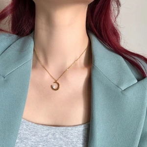 Minimalist gold crescent moon necklace with clear gemstone worn on a light blue suit