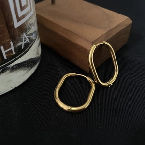 Detail view of oval gold geometric earrings featuring a polished 18K finish for women