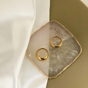 Polished gold-plated minimalist dome rings displayed on a luxury white stone tray