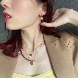 Golden double-layer Good Luck necklace and matching hoop earrings on a female model