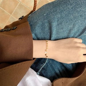 Elegante bracciale a catena dorata con ciondoli a disco luccicanti indossato con stile