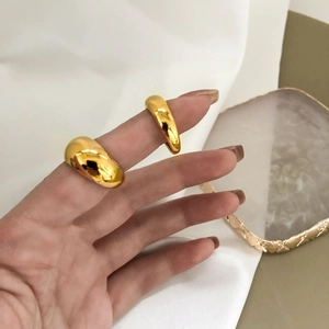 Polished chunky gold rings displayed on fingers over elegant silk and stone tray