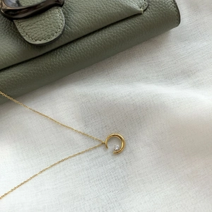 Detail shot of a gold crescent moon pendant necklace with a center clear gemstone