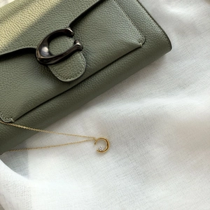 Minimalist gold moon pendant necklace with white stone on elegant linen and leather background