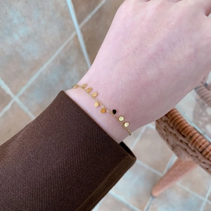 Dettaglio di un bracciale minimalista in oro con dischi rotondi lucidi sulla catena