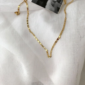 Dettaglio di una collana a catena piatta placcata in oro 14k con chiusura a moschettone
