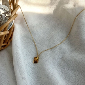 Detailaufnahme einer 14k vergoldeten Halskette mit Good Luck Gravur auf Anhänger